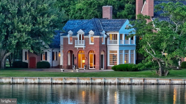 view of front of property with a water view, a balcony, and a front lawn