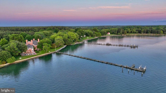 aerial view at dusk featuring a water view