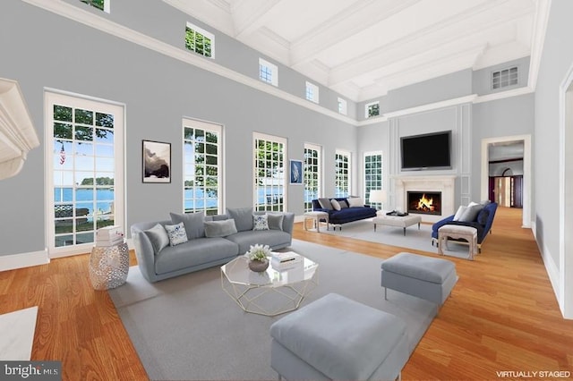 living room with beam ceiling, a towering ceiling, and light hardwood / wood-style flooring