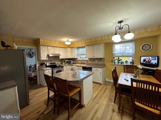 kitchen with pendant lighting, appliances with stainless steel finishes, white cabinets, light wood-type flooring, and an inviting chandelier