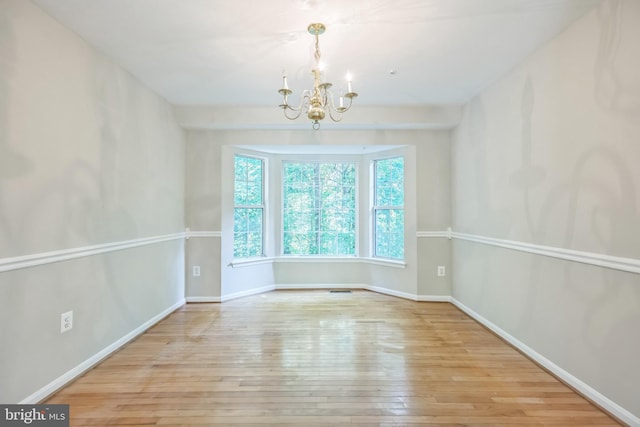 unfurnished room featuring a chandelier and light hardwood / wood-style floors