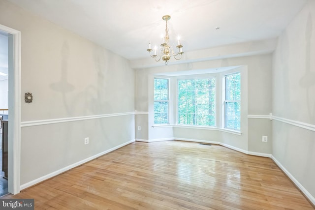 spare room featuring light hardwood / wood-style floors and a notable chandelier