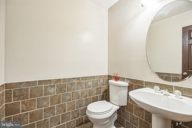 bathroom with tile walls, toilet, and sink