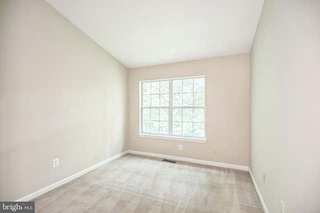 empty room featuring light colored carpet and vaulted ceiling