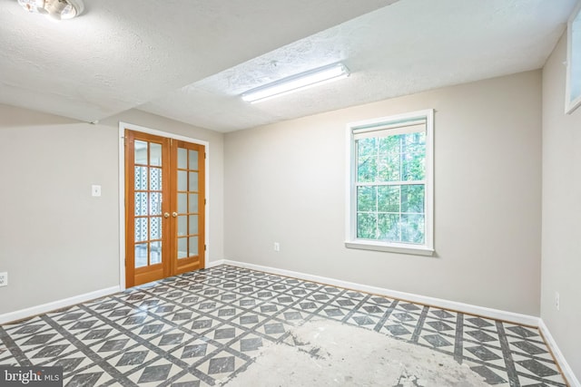 empty room featuring a textured ceiling and french doors