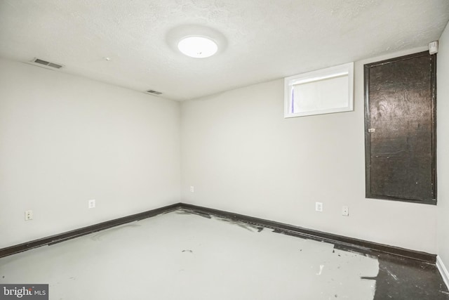 empty room with a textured ceiling and concrete floors