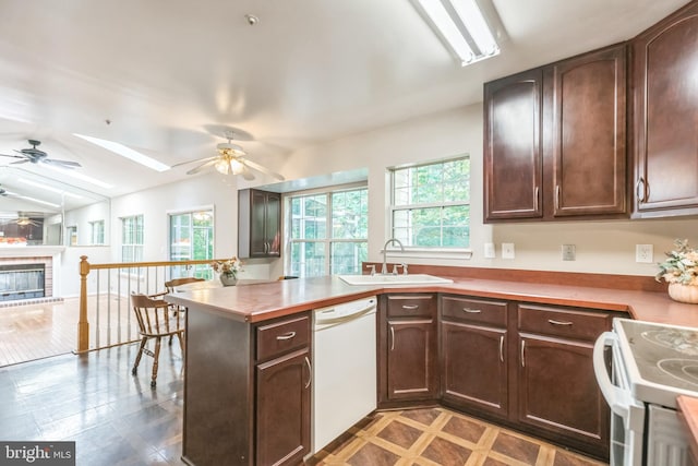 kitchen featuring a fireplace, white appliances, kitchen peninsula, sink, and ceiling fan