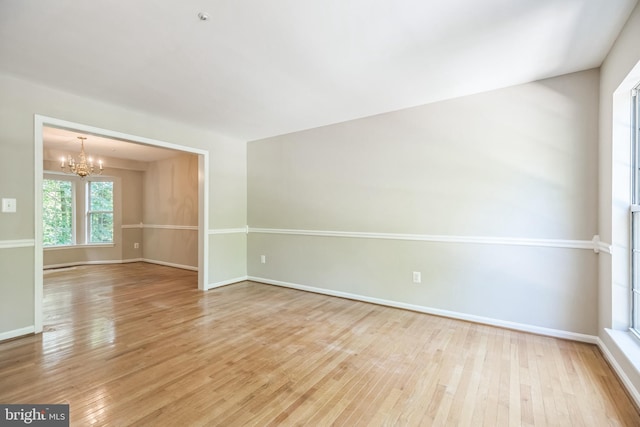 unfurnished room with an inviting chandelier and light hardwood / wood-style floors