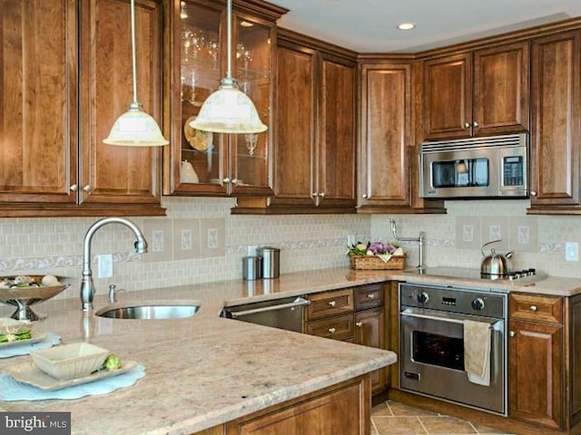 kitchen featuring light stone counters, tasteful backsplash, light tile floors, stainless steel appliances, and sink