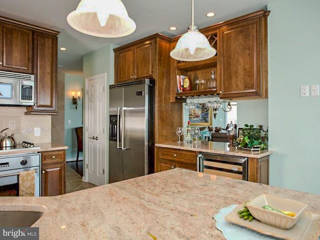 kitchen featuring appliances with stainless steel finishes, pendant lighting, beverage cooler, light stone countertops, and light tile flooring