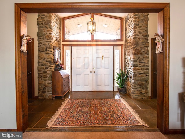 foyer entrance with dark carpet and lofted ceiling