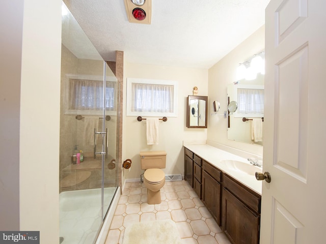 bathroom with a textured ceiling, toilet, vanity, baseboards, and a stall shower