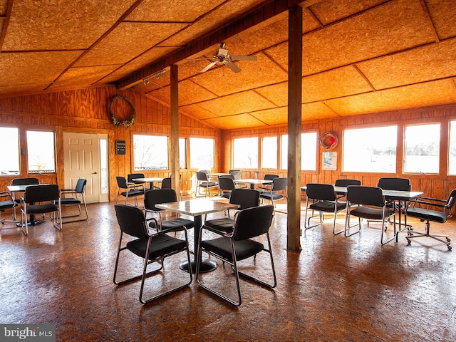 dining room with vaulted ceiling with beams, ceiling fan, and wood walls