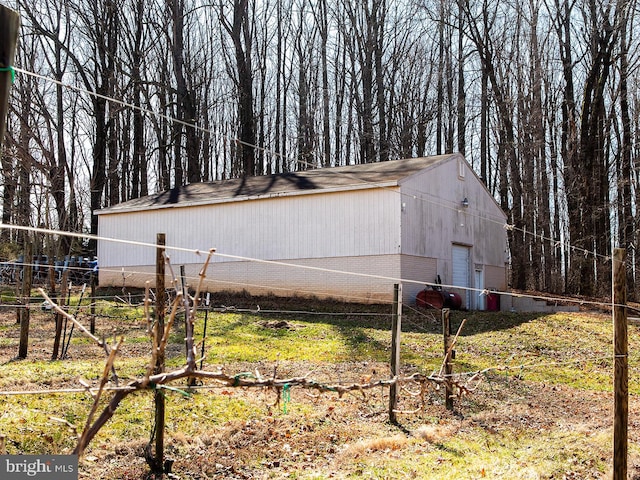 view of property exterior with an outbuilding, brick siding, fence, and a detached garage