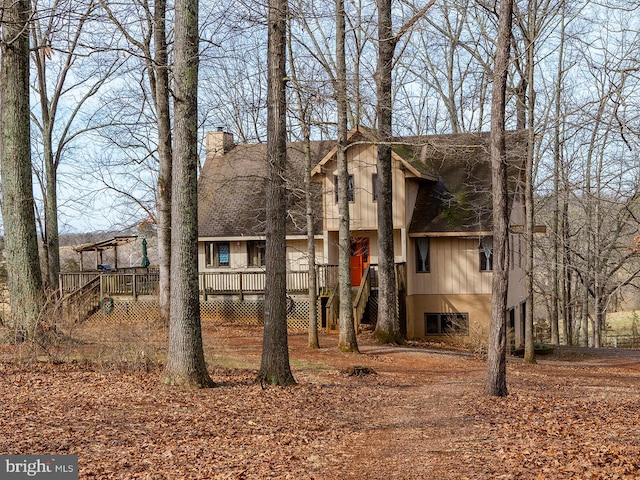 view of front facade featuring stairs, a chimney, and a wooden deck