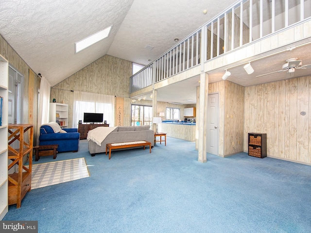 bedroom with carpet floors, a skylight, wooden walls, and a textured ceiling