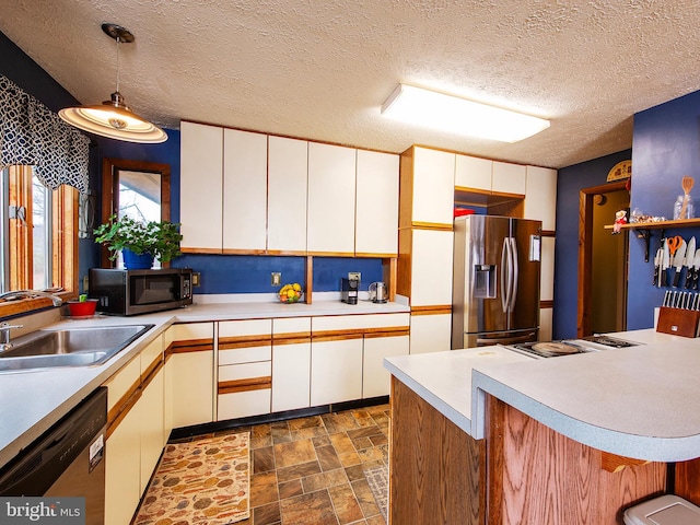 kitchen featuring white cabinetry, sink, stainless steel appliances, and decorative light fixtures