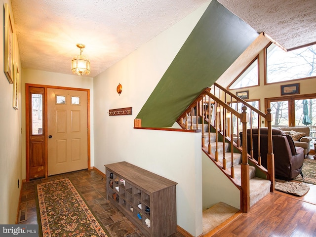 foyer with a notable chandelier, dark hardwood / wood-style floors, a textured ceiling, and vaulted ceiling