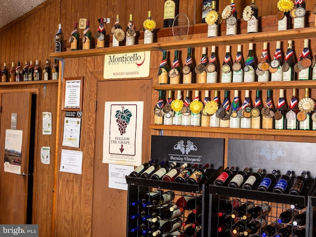 wine room featuring wooden walls and a textured ceiling