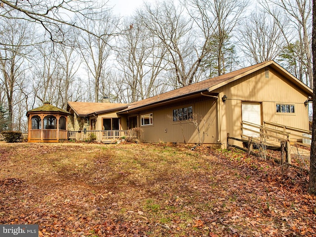 rear view of house featuring a chimney and a gazebo