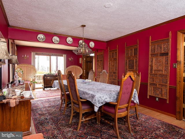 dining area with a textured ceiling, wood-type flooring, and ornamental molding