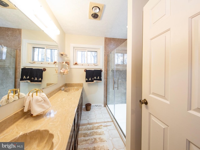 bathroom featuring tile patterned floors, vanity, a shower with shower door, and a textured ceiling