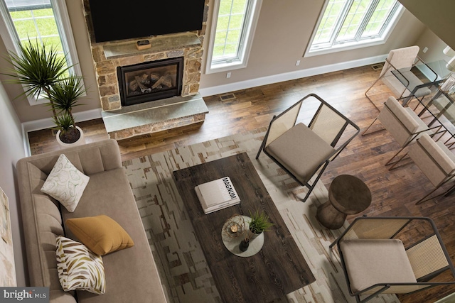 living room featuring dark hardwood / wood-style flooring, a stone fireplace, and plenty of natural light