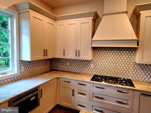 kitchen featuring backsplash, stainless steel gas stovetop, and premium range hood