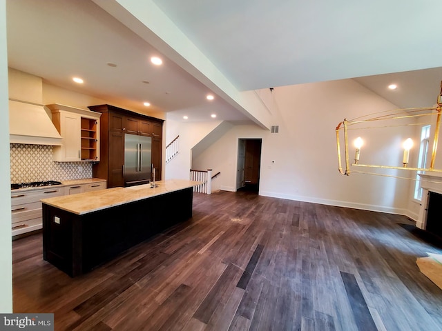 kitchen with backsplash, dark hardwood / wood-style floors, a kitchen island with sink, and appliances with stainless steel finishes