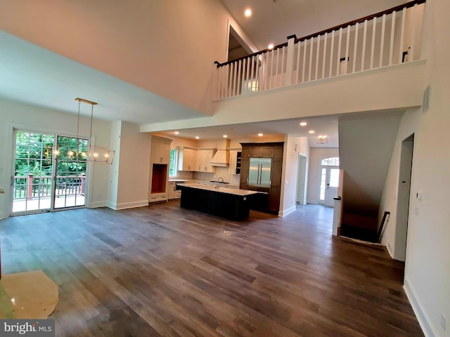 unfurnished living room with dark hardwood / wood-style flooring, a wealth of natural light, and a chandelier