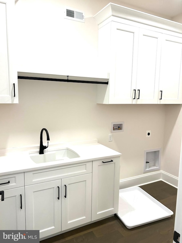 laundry room with dark wood-type flooring, sink, electric dryer hookup, washer hookup, and cabinets