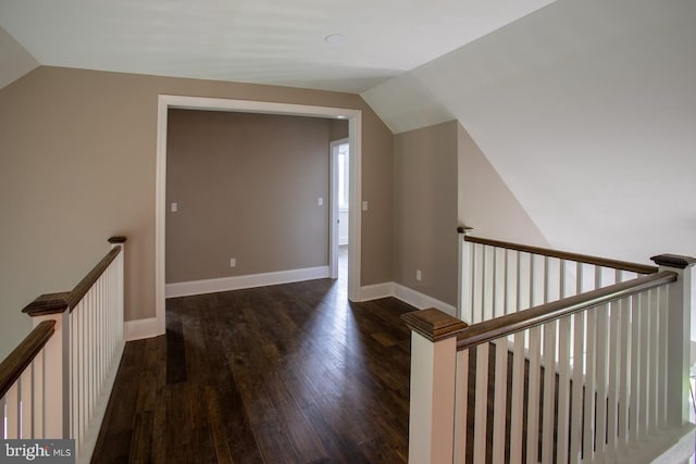 hall with lofted ceiling and dark wood-type flooring