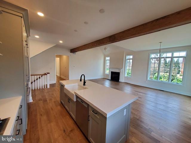 kitchen with an island with sink, sink, vaulted ceiling with beams, and light hardwood / wood-style flooring