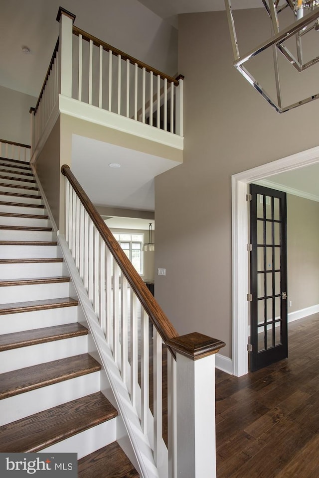 stairway featuring a towering ceiling and dark wood-type flooring