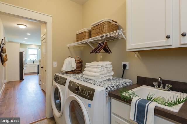 laundry area featuring cabinets, light hardwood / wood-style floors, sink, electric dryer hookup, and independent washer and dryer