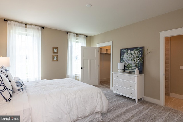 bedroom featuring light carpet, a spacious closet, and a closet