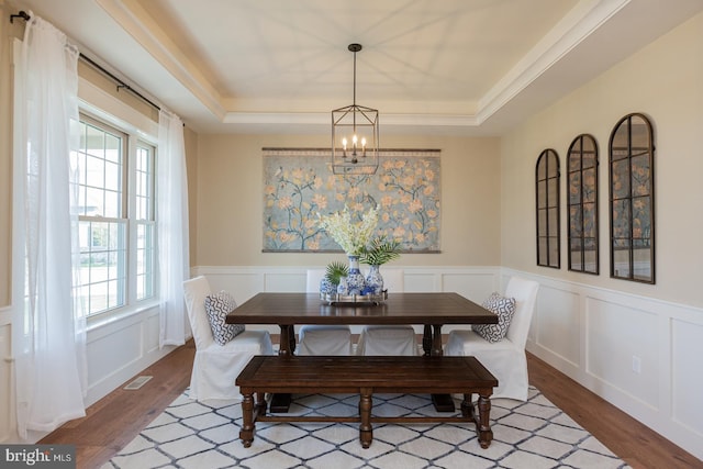 dining room with dark hardwood / wood-style flooring, an inviting chandelier, and a raised ceiling