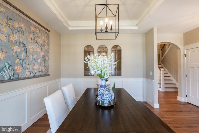 dining space with a notable chandelier, a raised ceiling, and dark hardwood / wood-style floors