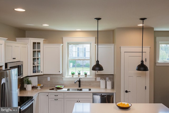 kitchen with backsplash, white cabinets, appliances with stainless steel finishes, and sink