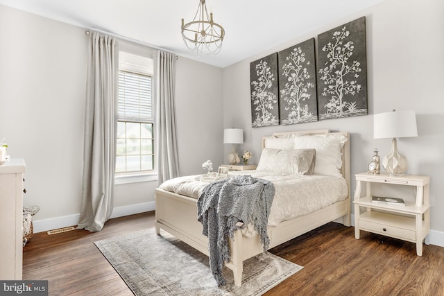 bedroom with dark hardwood / wood-style floors and a chandelier