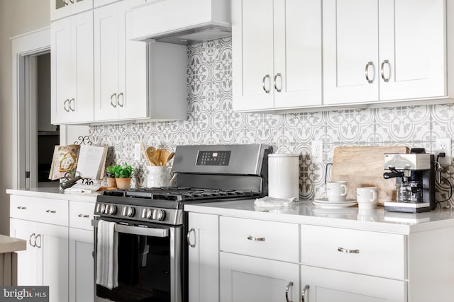 kitchen featuring white cabinets, backsplash, gas stove, and custom exhaust hood