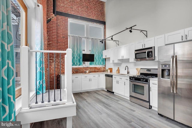 kitchen featuring white cabinetry, track lighting, appliances with stainless steel finishes, and light wood-type flooring