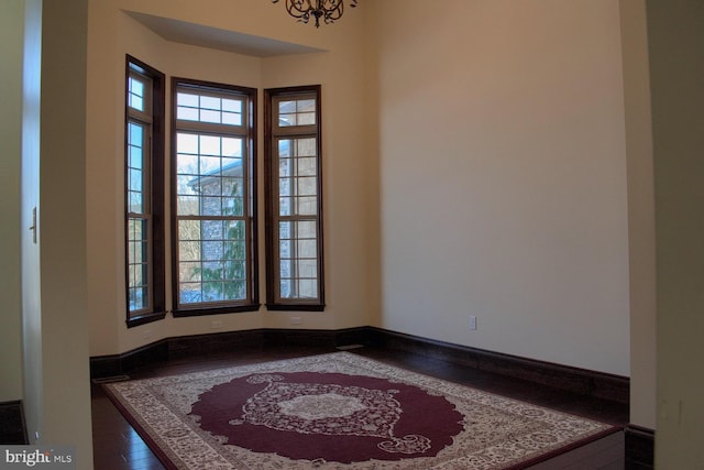 spare room with dark hardwood / wood-style flooring and an inviting chandelier