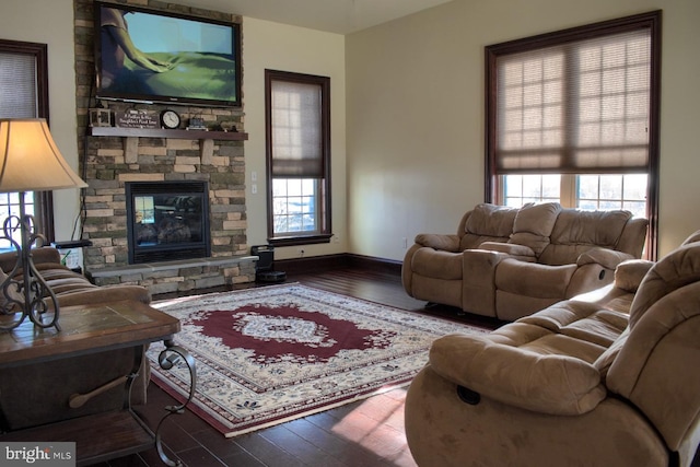 living room with hardwood / wood-style floors, a stone fireplace, and a wealth of natural light