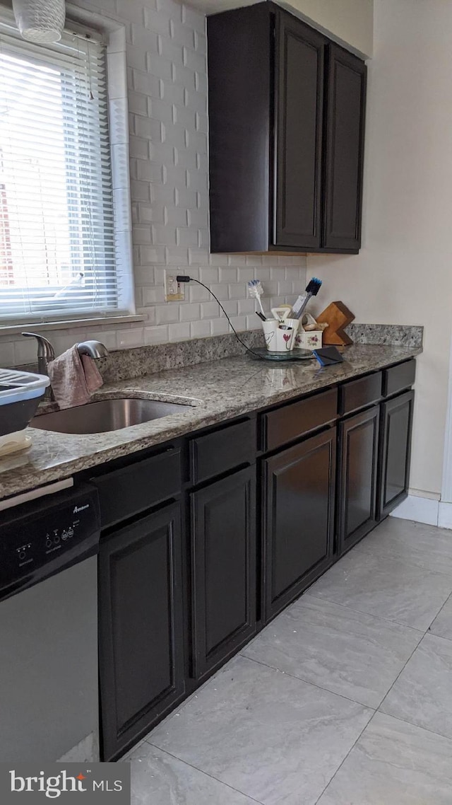 kitchen with dark stone countertops, dishwashing machine, sink, and dark brown cabinets