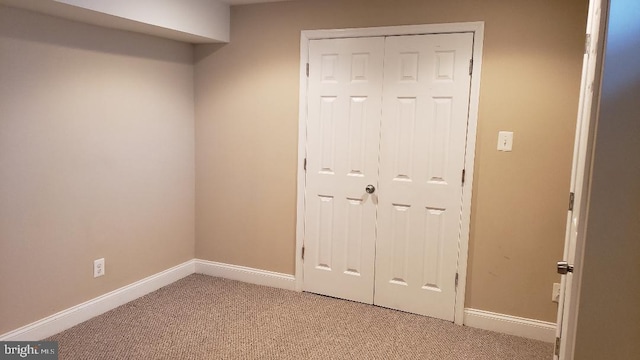 unfurnished bedroom with light colored carpet and a closet