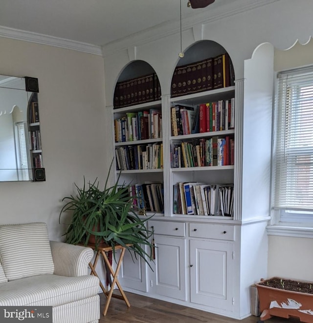 living area featuring dark wood-type flooring, ceiling fan, and crown molding