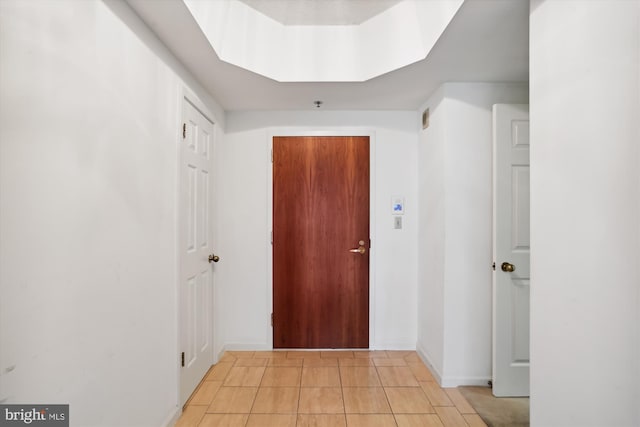 hallway featuring a skylight and light tile floors