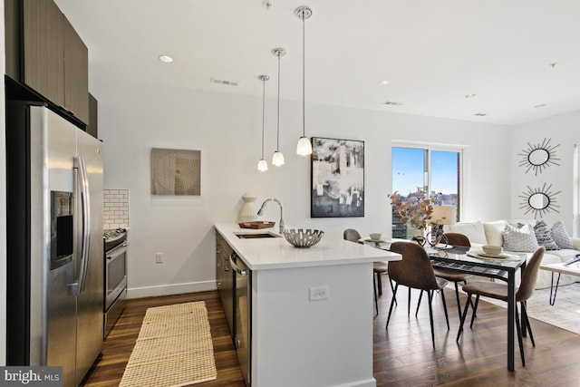 kitchen featuring dark hardwood / wood-style flooring, dark brown cabinetry, stainless steel appliances, sink, and hanging light fixtures