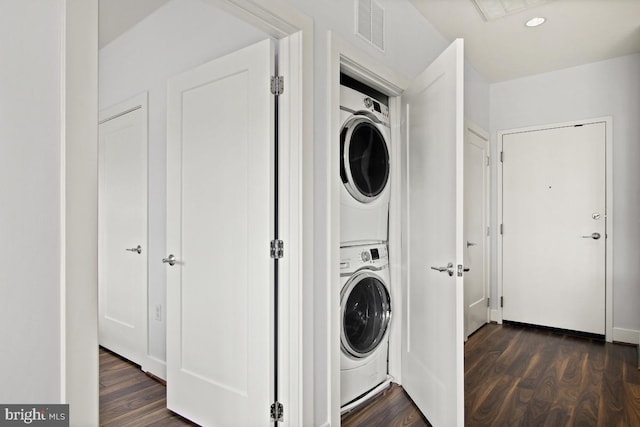 clothes washing area with dark hardwood / wood-style flooring and stacked washer and dryer